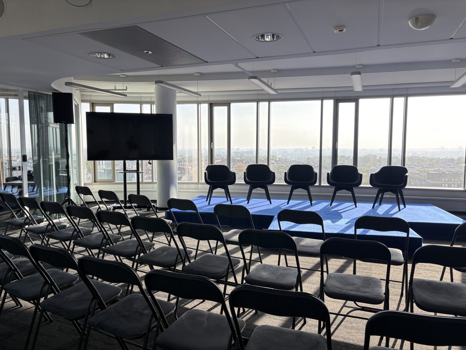 Sala konferencyjna Warszawa w układzie teatralnym na 80 osób — rzędy krzeseł, scena dla panelistów i ekran, Zebra Tower, Mokotowska 1